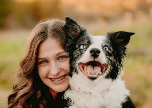 A happy young girl smiling with her black and white Border Collie, showcasing the strong bond between pets and their owners. Perfect for illustrating home remedies for teething puppies.